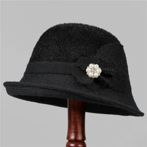 Detail of black knitted cloche hat with a white pearl and crystal flower accent