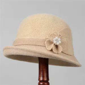 Detailed close-up of khaki knit bucket hat with pearl and rhinestone flower decoration