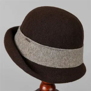 Detailed close-up of dark brown wool felt bucket hat with knitted band and metal logo