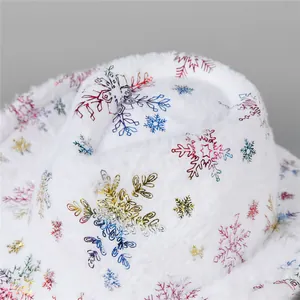 Close-up of white plush Christmas bucket hat with colorful metallic snowflake patterns