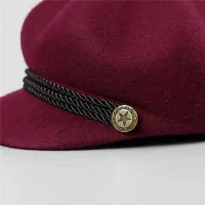 Détail de casquette gavroche bordeaux avec bouton étoile bronze vintage et cordon tressé