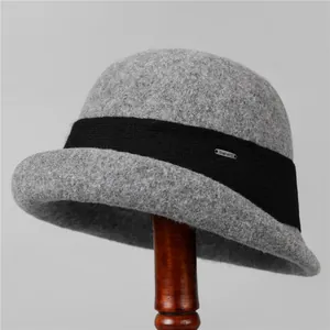 Detailed macro view of dark grey wool felt cloche hat with black band and metal brand tag