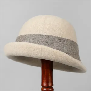 Detail of wool felt bucket hat with knitted band and metallic logo plate on wooden stand