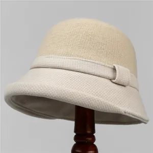 Dettaglio di un elegante cappello cloche bicolore su un supporto in legno scuro