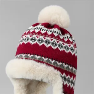 Détail du bonnet tricoté rouge avec motifs géométriques et cache-oreilles en fausse fourrure