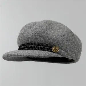 Détail de la casquette gavroche en laine avec bride tressée et bouton en laiton vintage