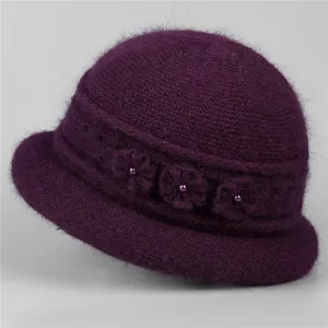Close-up of deep purple knit winter hat with plush fur texture and floral decorations