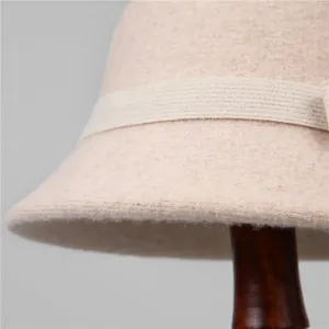 Detailed close-up of beige wool felt cloche hat with textured ribbon bow detail