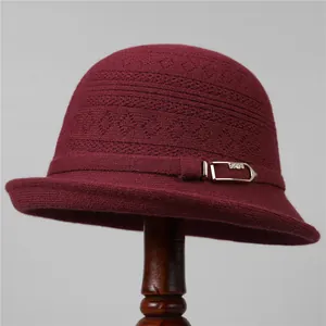 Detalle de gorro de punto burdeos con flores caladas y hebilla dorada de moda elegante