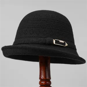 Detalle de gorro cloche de punto negro con hebilla dorada de FASHION y textura de lana