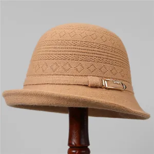 Detalle de gorro de punto color camel con textura geométrica y hebilla dorada elegante