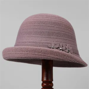 Dettaglio di cappello pescatore in maglia con tre fiori in tessuto e piccoli strass