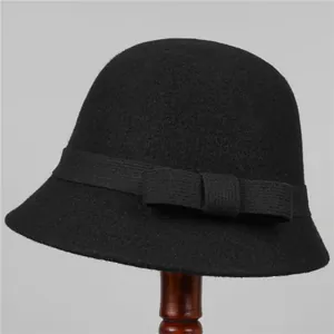 Close-up of black wool felt hat featuring a decorative bow on a wooden stand