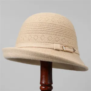 Detalle de sombrero de punto beige con elegante hebilla de metal dorado en soporte