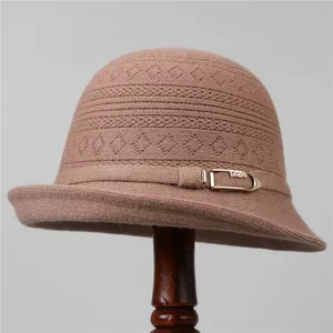 Primer plano de sombrero cloche de punto rosa con texturas y hebilla dorada decorativa