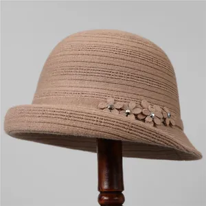 Dettaglio di un cappello lavorato a maglia kaki con fiore in rilievo e cristallo