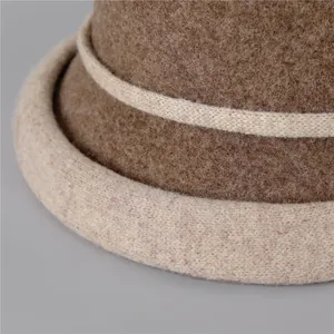 Détail macro de la texture en laine feutrée et bord roulé beige contrasté du chapeau