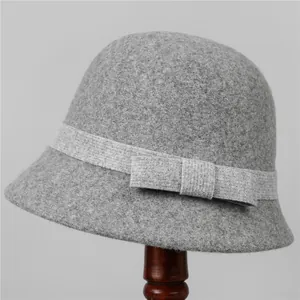 Detailed texture of grey wool cloche hat featuring a delicate bow on a wooden stand