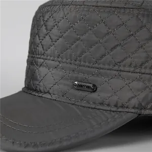 Detail of dark grey quilted flat cap showing diamond stitching and side decorative buckle