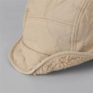 Close-up of khaki quilted fabric and warm beige sherpa fleece lining on winter aviator hat