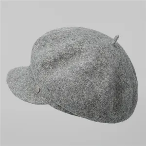 Close-up of grey wool beret texture with decorative silver button and peak top