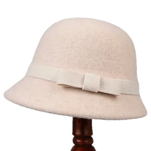 Elegant beige wool cloche hat for women with a vintage bow accent on a wooden stand