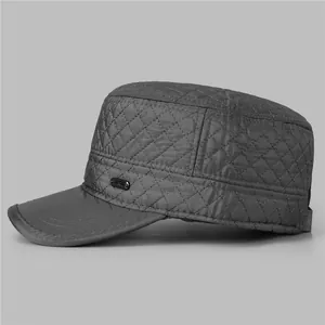 Detail of dark grey quilted flat cap showing diamond stitching and metal emblem