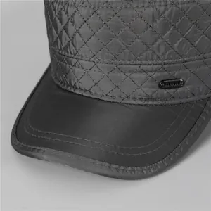 Detail of grey quilted flat cap showing diamond stitching and metal tag logo