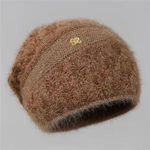 Detalle de un gorro de punto marrón suave con textura de felpa y emblema de logo dorado