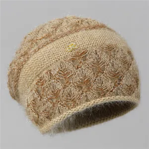 Detalle del gorro de punto color avena con lana esponjosa y adorno metálico dorado S2