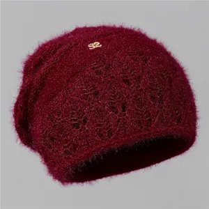 Detalle del gorro de punto granate con textura calada y hebilla metálica dorada en S