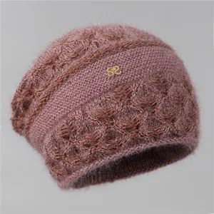 Detalle de gorro de punto color malva con emblema S dorado y pedrería de cristal