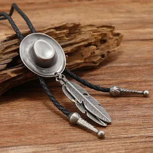 Λεπτομέρεια bolo tie με καπέλο cowboy και φτερά σε φόντο από ρουστίκ ξύλο