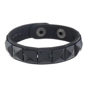 Dettaglio di bracciale punk in pelle nera con borchie a piramide lucide e bottoni a scatto