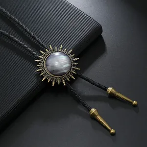 Détail macro du pendentif bolo tie soleil vintage avec pierre précieuse sur cuir noir