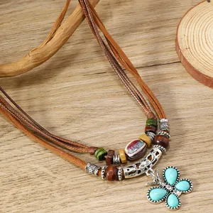 Detalle de collar bohemio de capas con colgante de mariposa turquesa sobre madera