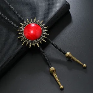 Détail d'une cravate bolo vintage avec motif soleil, pierre rouge et cordon en cuir noir