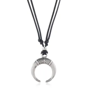 Detailed view of retro silver crescent horn pendant with intricate wave patterns and black cord
