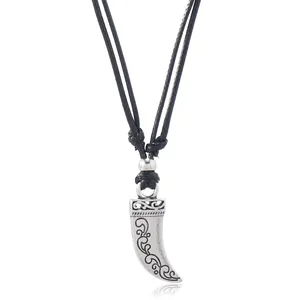 Macro view of vintage silver horn pendant with intricate floral engravings on black rope