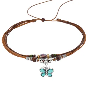 Detalle del colgante de mariposa bohemia con toques turquesas y cuentas de madera de colores
