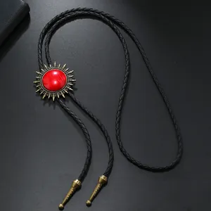 Détail de cravate bolo vintage avec boucle soleil en métal et pierre rouge sur corde