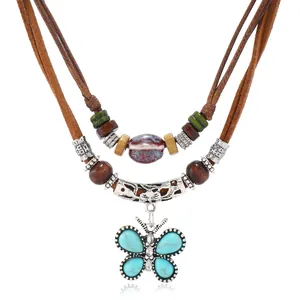 Detalle de un collar bohemio de varias capas con mariposa turquesa y cuentas de madera