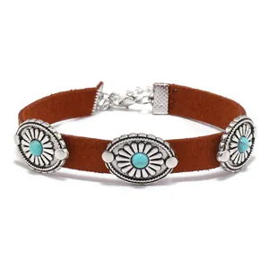 Detail of bohemian brown suede bracelet with vintage turquoise sunburst metal charms