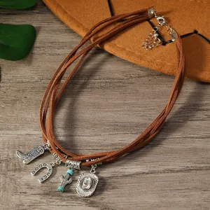 Détail d'un collier bohème vintage avec breloques de botte de cowboy et cactus