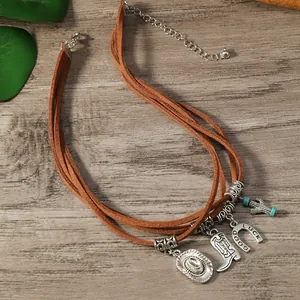 Détail du choker en daim style western avec pendentifs vintage chapeau, botte et fer à cheval