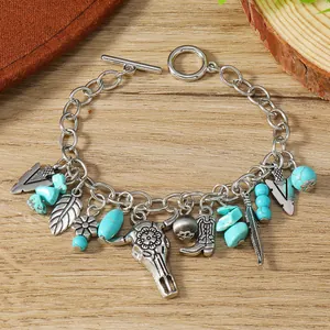 Detail of vintage silver chain bracelet with turquoise charms and cattle skull on wood