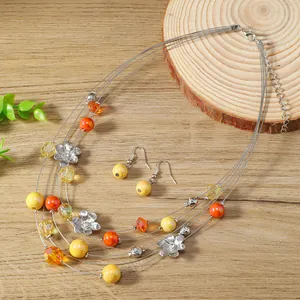 Colorful multi-layer floral necklace and earring set with wire beads on a wooden background