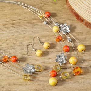 Detail of colorful multilayer flower necklace and earrings set on natural wood background