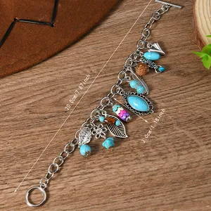 Detail of vintage silver bracelet with turquoise beads, metal feathers and leaves charm