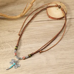 Detalle del colgante de libélula plateada con piedras azules y cordón trenzado